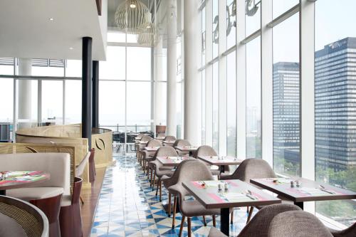 a restaurant with tables and chairs and large windows at All Seasons Jakarta Thamrin in Jakarta