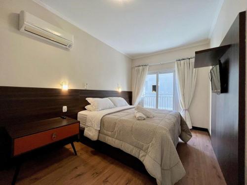 a bedroom with a large bed and a window at Apartamentos Onze1 no CENTRO by Achei Gramado in Gramado