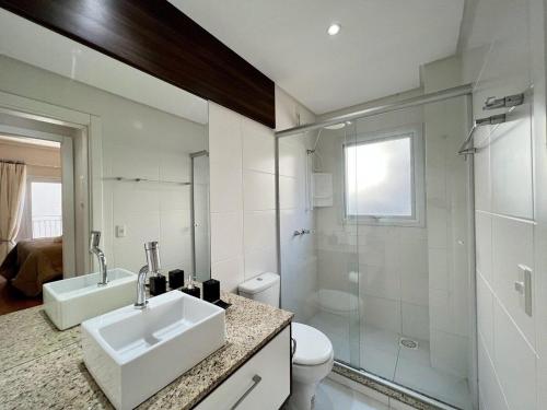 a bathroom with a sink and a toilet and a shower at Apartamentos Onze1 no CENTRO by Achei Gramado in Gramado