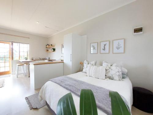 een witte slaapkamer met een groot bed en een keuken bij Upmarket off grid cottage on organic farm in secure estate in Howick