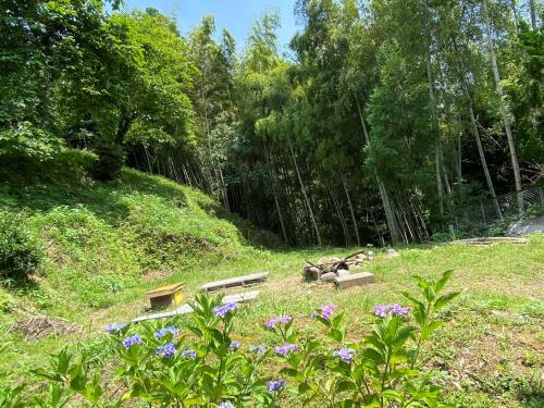 a park with benches and flowers in the grass at 体験型古民家宿 旅ノ舎 in Nissaka