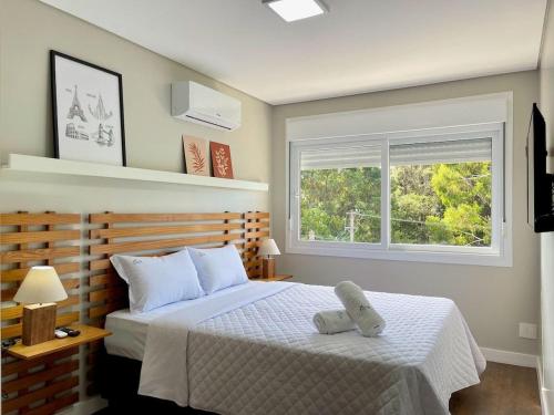 a bedroom with a bed and a window at Apartamentos Quinta do Palácio by Achei Gramado in Canela