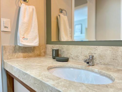 a bathroom with a sink and a mirror at Apartamentos Quinta do Palácio by Achei Gramado in Canela
