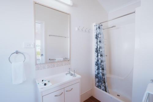 a white bathroom with a sink and a shower at BIG4 Breeze Holiday Parks - Bargara in Bargara