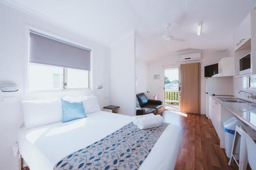 a white bedroom with a large bed and a kitchen at BIG4 Breeze Holiday Parks - Bargara in Bargara