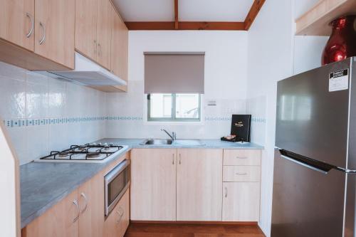 a kitchen with wooden cabinets and a stainless steel refrigerator at Discovery Parks - Bargara in Bargara