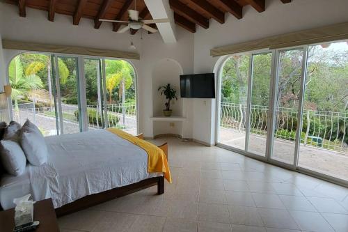 a bedroom with a bed and a tv and windows at Villa Martha Garza Blanca - Heated Pool, Chef & Full Staff Included in Puerto Vallarta