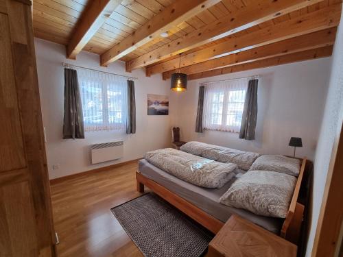 1 dormitorio con 2 camas y 2 ventanas en Ferienhaus Andrea AD0, en Blatten bei Naters