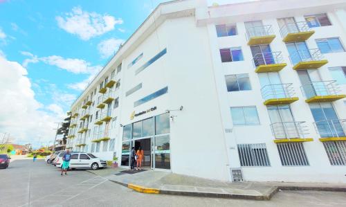 un edificio blanco con gente parada fuera de él en Apto con Piscina a 5min del Parque Nacional Del Café, en Montenegro