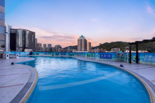 a large swimming pool with a city in the background at Guangdong Hotel (Zhuhai) in Zhuhai