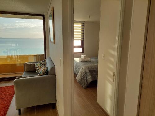 a bedroom with a bed and a chair and a window at Departamento con preciosa vista al mar y ciudad in Puerto Montt