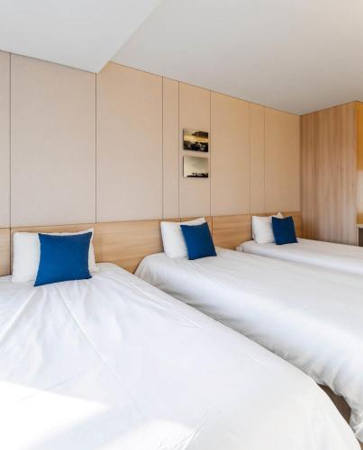 a room with three beds with blue pillows at Hotel bridge Seogwipo in Seogwipo