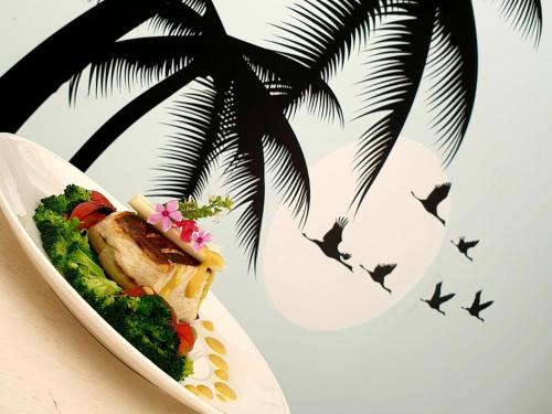a plate of food on a table with a palm tree at Coco Villa in Thoddoo