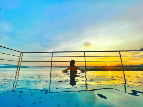 a woman sitting in a swimming pool at sunset at Langkawi Seaview Cube w/ Rooftop Pool in Kuah