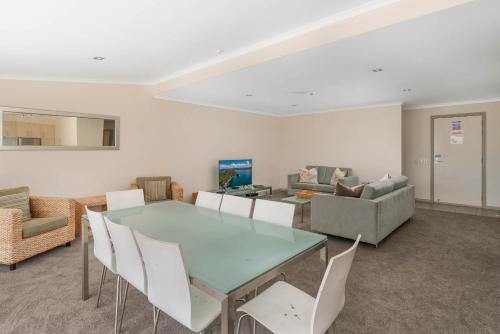 a dining room with a glass table and white chairs at Crow's Nest Apartments in Whitianga