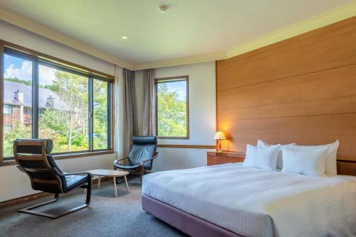 a hotel room with a bed and two chairs at Hotel Sierra Resort Hakuba in Hakuba