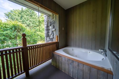 uma banheira num quarto com uma grande janela em Hotel Sierra Resort Hakuba em Hakuba