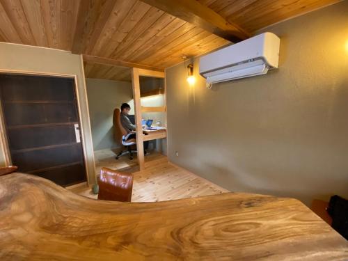 a room with a person sitting at a desk with a laptop at 体験型古民家宿 旅ノ舎 in Nissaka