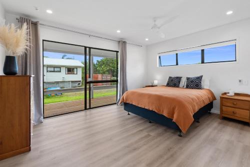 a bedroom with a bed and a large window at Waimanu Bliss Escape - Point Wells Holiday Home in Omaha