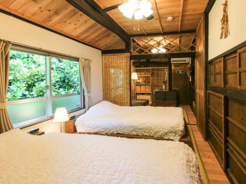 大宜味村にあるNerome#01 Okinawan Traditional House in YAMBARU,bcのベッドルーム1室(ベッド2台、窓付)