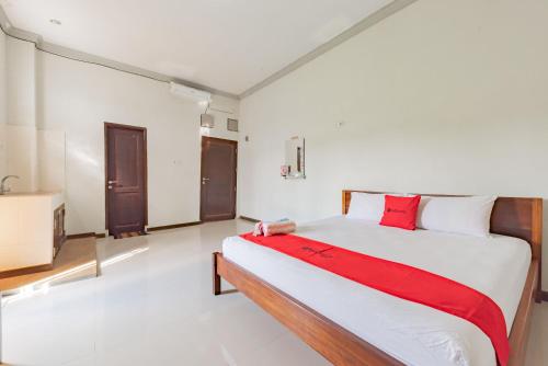 a bedroom with a large bed with a red blanket at RedDoorz near GOR Sempaja Samarinda in Samarinda