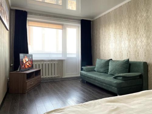 a living room with a green couch and a television at 1-комнатная квартира, центр, супермаркет Сокол in Petropavlovsk
