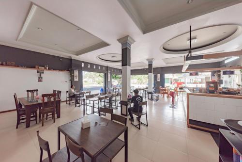 un restaurante con mesas y sillas y gente sentada en él en RedDoorz near GOR Sempaja Samarinda, en Samarinda