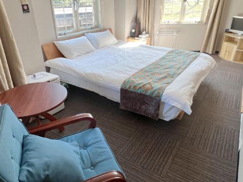 a bedroom with a bed and a table and a chair at Hakuba Sun Valley Hotel in Hakuba