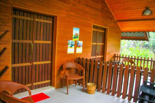 a porch of a wooden cabin with chairs and a door at Machcha Lodge Sigiriya in Sigiriya