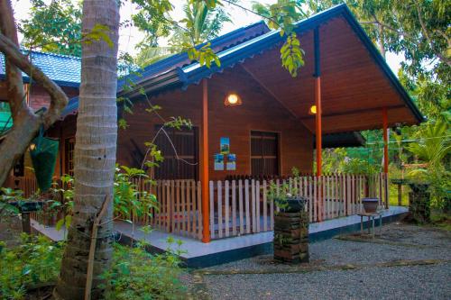a small wooden house with a fence in front of it at Machcha Lodge Sigiriya in Sigiriya