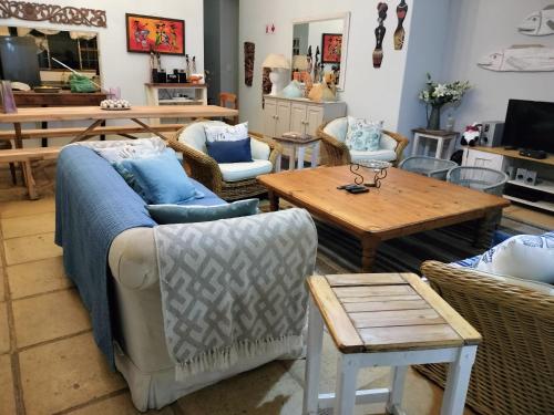 uma sala de estar com um sofá, cadeiras e uma mesa em Laughing Gecko Lodge2 em Southbroom