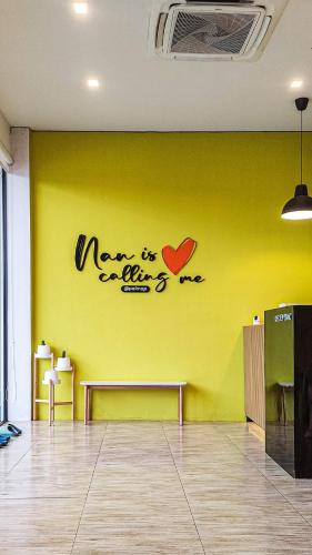 a yellow wall with a sign on it with a heart on it at Paknap Hostel in Nan