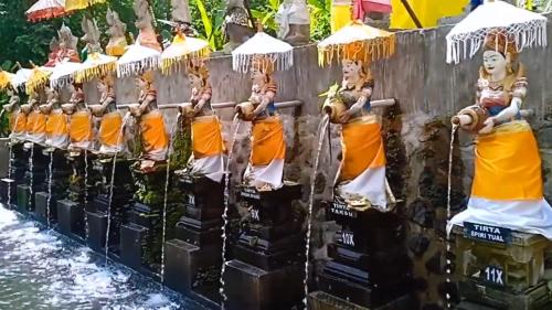 un gruppo di statue di Buddha su un muro vicino all'acqua di Penglukatan Dasa Mala Lan Tirta Widiadari a Susut
