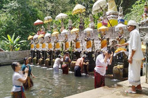 a group of people standing in the water at Penglukatan Dasa Mala Lan Tirta Widiadari in Susut