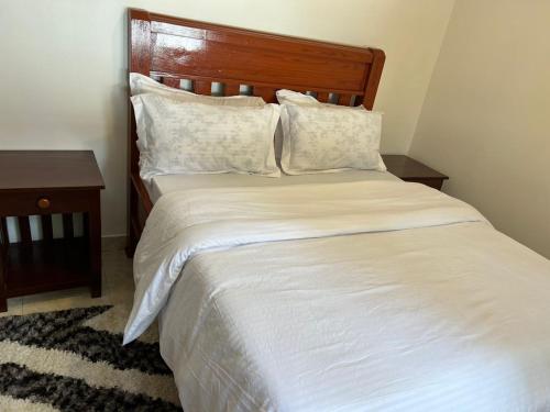 a bedroom with a white bed with a wooden headboard at ArushaWest in Arusha