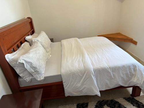 a bed with white sheets and pillows on it at ArushaWest in Arusha