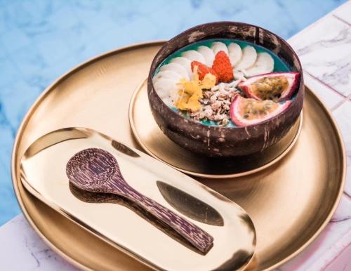 a bowl of food on a gold plate with a spoon at Carapace Residents Huahin-Khaotao in Khao Tao