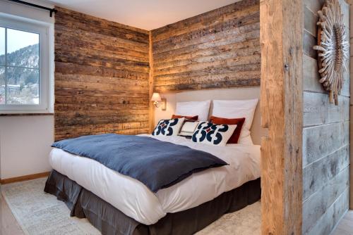a bedroom with a wooden accent wall and a bed at MOUNTAIN LODGE - Neueröffnung 2023 moderner Premium Wellness Appartments, Ski-in Ski-out, Family owned in Oberjoch