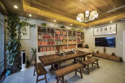 a dining room with a table and benches and bookshelves at Qianxun Tea House & Homestay in Wuyishan