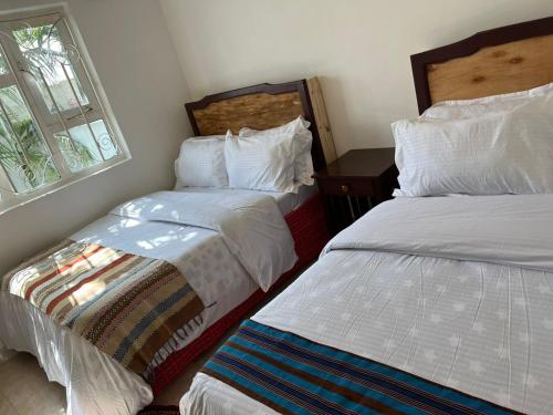 - une chambre avec 2 lits et une fenêtre dans l'établissement ArushaWest, à Arusha