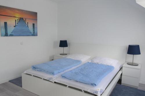 a white bed with two blue pillows on it at Baltic Nr. 24 in Scharbeutz