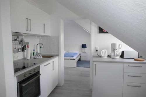 a white kitchen with white cabinets and a staircase at Baltic Nr. 24 in Scharbeutz