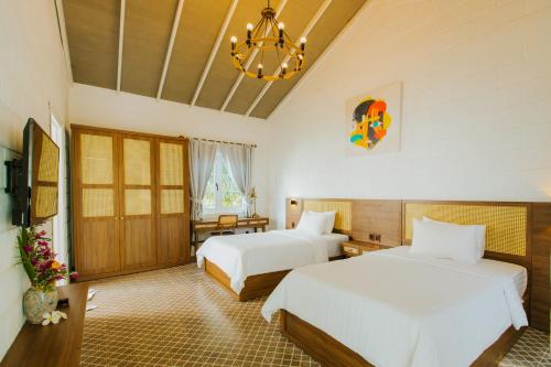 1 dormitorio con 2 camas y lámpara de araña en Perolas Villas Resort Powered by ASTON, en Phan Thiet