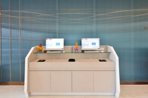 a desk with two computer monitors on top of it at Centre Point Prime Hotel Pattaya in Pattaya North
