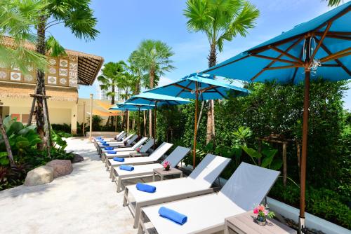 a row of lounge chairs and umbrellas on a patio at Centre Point Prime Hotel Pattaya in North Pattaya