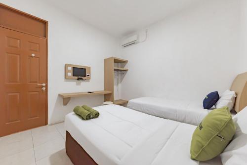 a hotel room with two beds and a tv at Urbanview Hotel Cozy Samarinda by RedDoorz in Samarinda