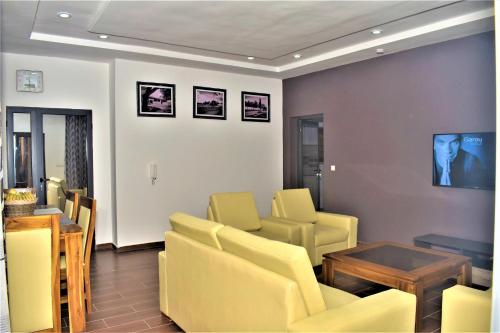 - une salle d'attente avec des chaises jaunes et une table dans l'établissement RÉSIDENCE BELLEVUE SITO AIPORT- Lomé, à Lomé