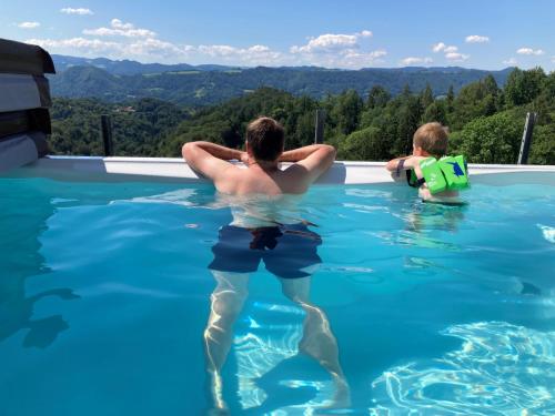 a man and a child swimming in a swimming pool at Ferienwohnung Traumaussicht in Leutschach