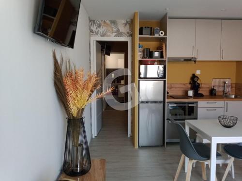 une cuisine avec une table et un vase avec des fleurs. dans l'établissement Appart cosy, 4 pers, terrasse et parking, 300m plage Clémenceau, près commerces, La Tranche sur Mer - FR-1-357-285, à La Tranche-sur-Mer
