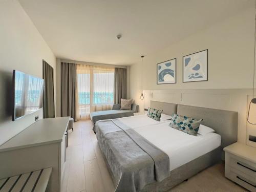 a bedroom with a large bed and a couch at GRIFID Moko Beach - 24 Hours Ultra All Inclusive & Private Beach in Golden Sands